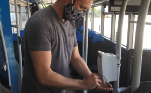 Man using hand sanitiser on bus