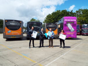 Picture of people stood in front of three Resding Buses holding tickets