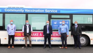 Stephensons of Essex and NHS staff stood in front of the mobile vaccination bus